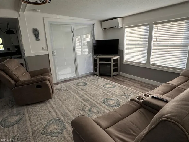 Living room with wood finished floors, a mini split for heating / cooling, and a textured ceiling