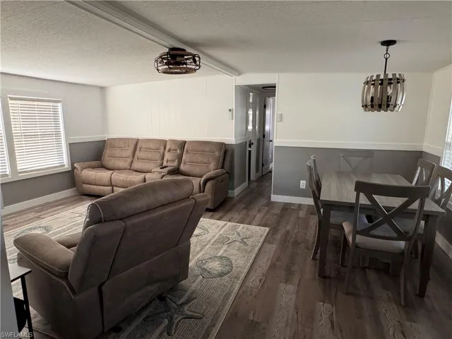 Living area with a textured ceiling, dark wood finished floors, and a chandelier
