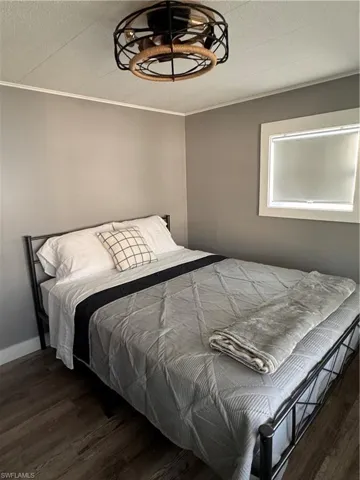 Bedroom with dark wood-style flooring, a textured ceiling, and crown molding
