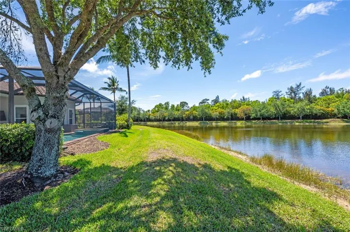 View of yard featuring a water view, an outdoor pool, and a lanai