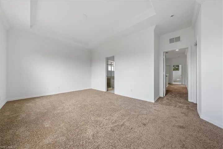 Carpeted spare room with crown molding and a tray ceiling