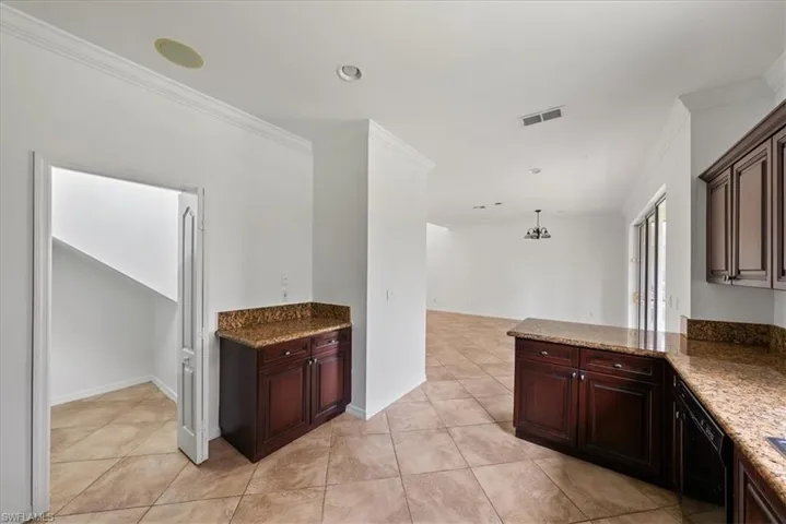 Kitchen with dishwasher, decorative light fixtures, crown molding, and light tile patterned floors