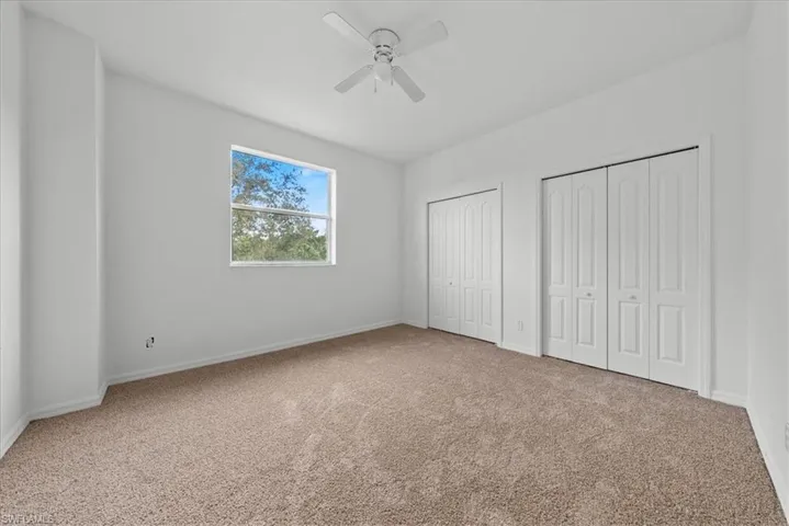Unfurnished bedroom featuring ceiling fan, multiple closets, and carpet flooring