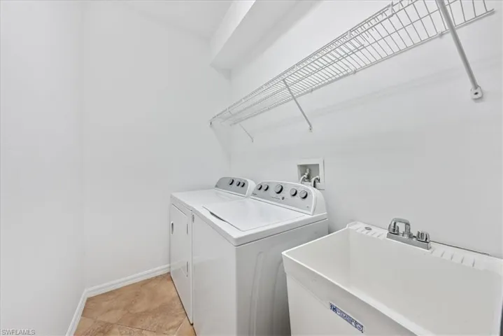 Laundry room with washer and dryer, sink, and light tile patterned floors
