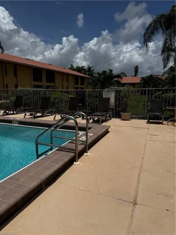 Community Pool with lots of seating and deck area, plus a grass area behind.