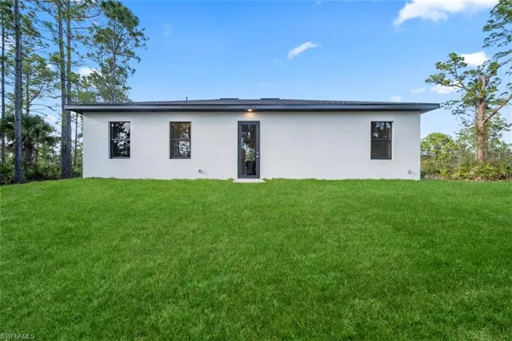 Rear view of house with a yard and stucco siding