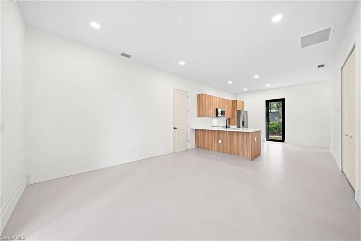 Kitchen featuring light countertops, a peninsula, open floor plan, finished concrete floors, and recessed lighting