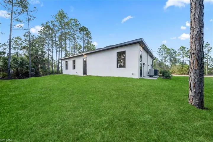 Rear view of house featuring a lawn and stucco siding