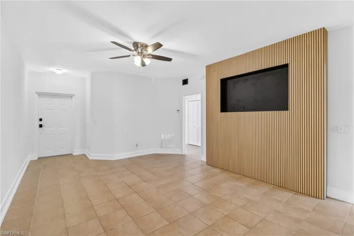 Empty room featuring an accent wall, ceiling fan, and light tile patterned flooring