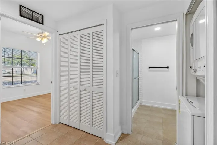 Full bathroom featuring a closet, a shower stall, a ceiling fan, and stacked washer / dryer