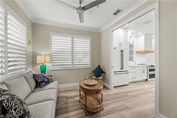 Living room with ceiling fan, light wood-type flooring, and ornamental molding