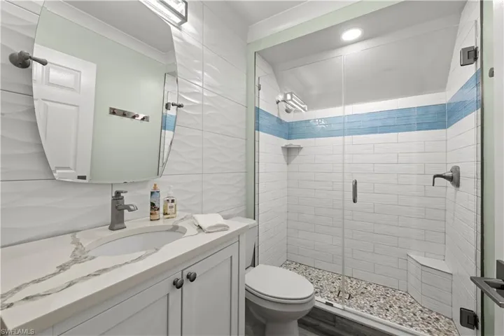 Bathroom featuring a shower with shower door, vanity, toilet, and ornamental molding