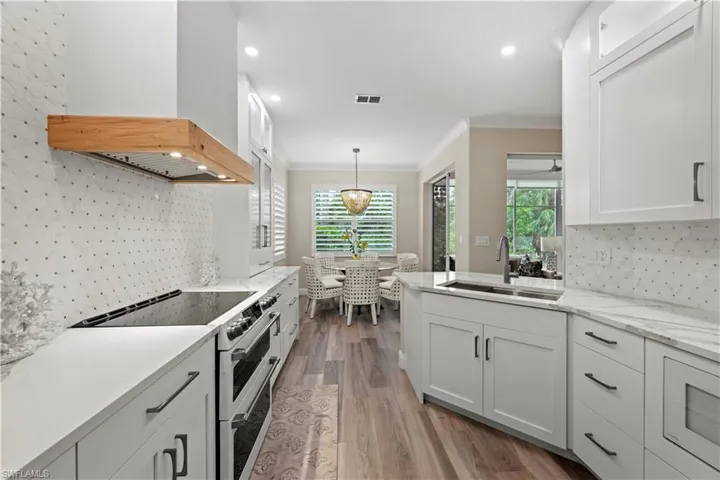Kitchen featuring white cabinets, high end stainless steel range, sink, and light wood-type flooring