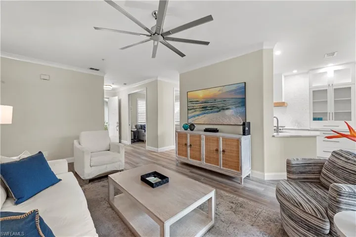 Living room with ornamental molding, wood-type flooring, and ceiling fan
