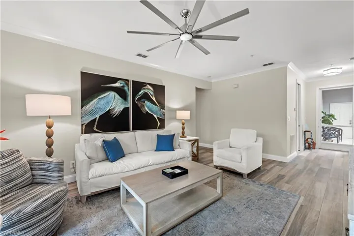 Living room featuring ceiling fan, wood-type flooring, and crown molding