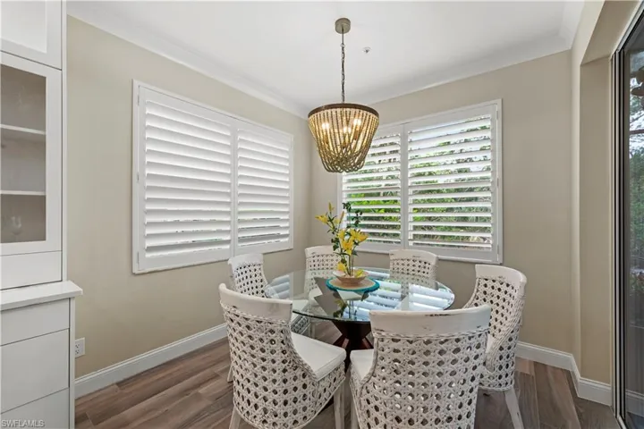Dining room with dark wood-type flooring, a chandelier, and ornamental molding