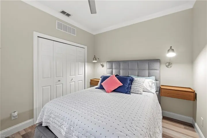 Bedroom with a closet, light wood-type flooring, ceiling fan, and crown molding