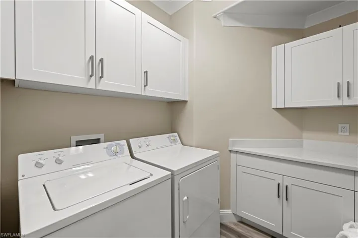 Laundry room with hardwood / wood-style floors, cabinets, and washer and dryer