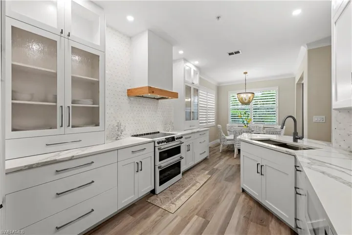 Kitchen with sink, white cabinetry, custom range hood, and double oven range