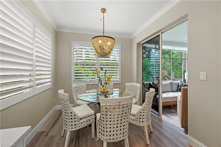Dining space with ornamental molding, a wealth of natural light, dark wood-type flooring, and a chandelier