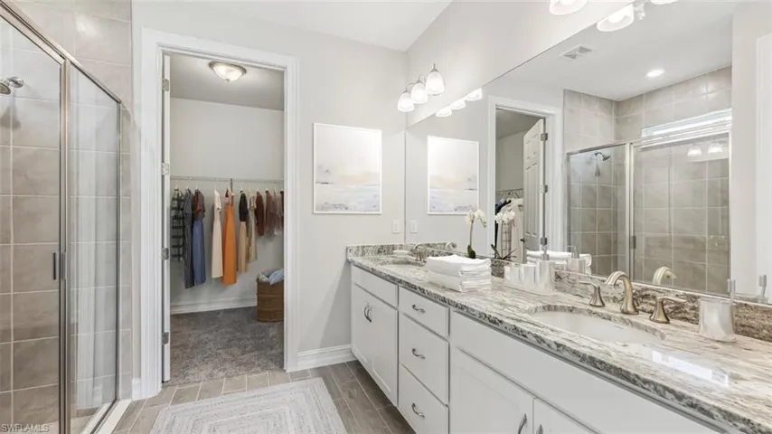 Bathroom featuring walk in shower, tile flooring, double sink, and vanity with extensive cabinet space