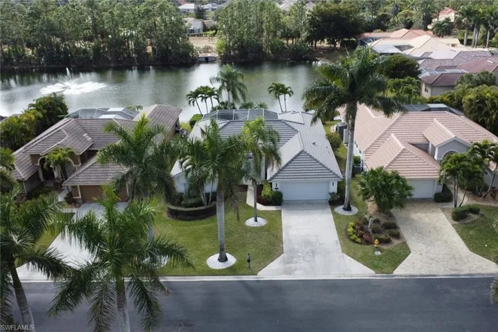Aerial view of residential area with a large body of water and a tree filled landscape