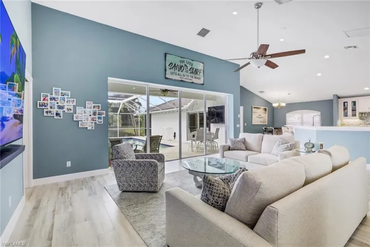 Living area with ceiling fan, a chandelier, light wood-style floors, plenty of natural light, and lofted ceiling