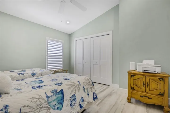 Bedroom with vaulted ceiling, light wood finished floors, ceiling fan, and a closet