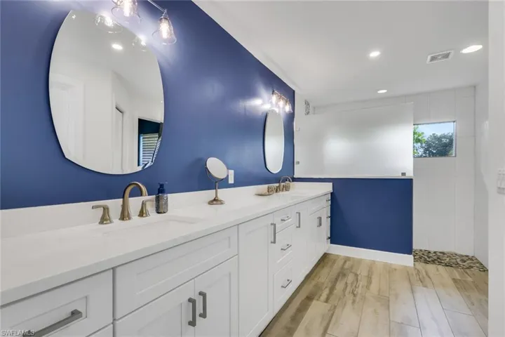 Bathroom with double vanity, light wood-type flooring, recessed lighting, and a walk in shower