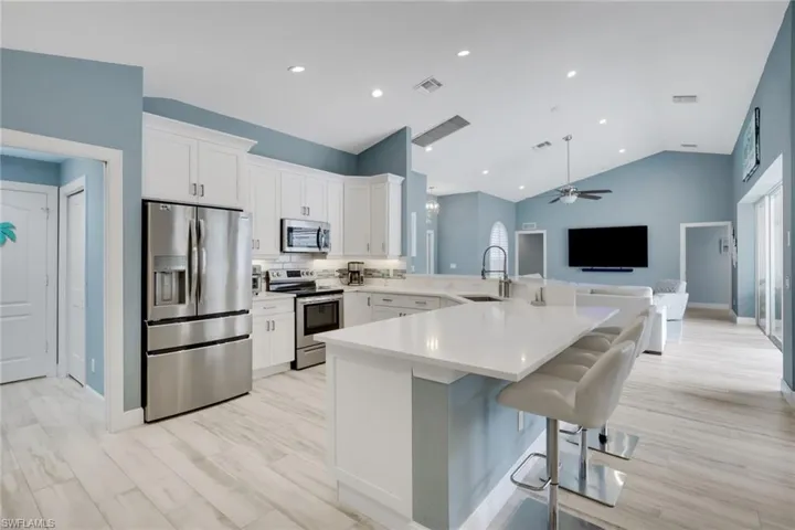 Kitchen with stainless steel appliances, a peninsula, a kitchen breakfast bar, white cabinetry, and open floor plan