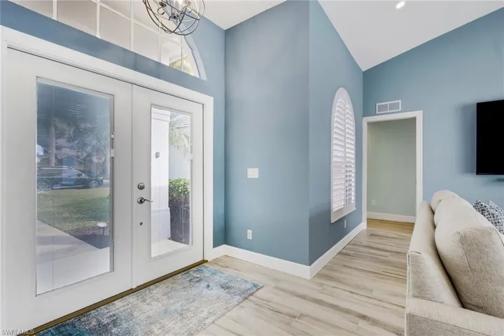 Entrance foyer featuring wood finished floors, french doors, a chandelier, and lofted ceiling
