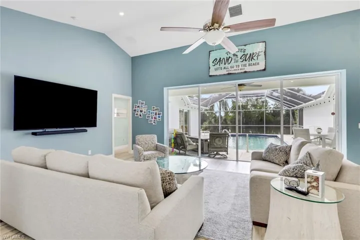 Living room with a sunroom, vaulted ceiling, wood finished floors, and ceiling fan