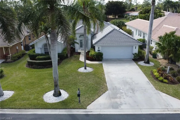 View of front of home with an attached garage, driveway, a front lawn, a tiled roof, and stucco siding