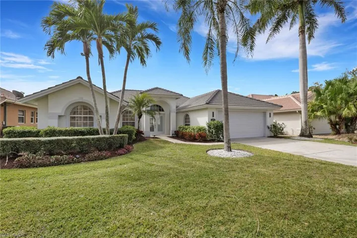 View of front of house featuring a front yard, stucco siding, driveway, a garage, and a tiled roof