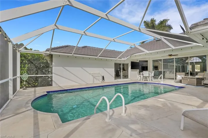 Outdoor pool with glass enclosure, a sunroom, and a patio