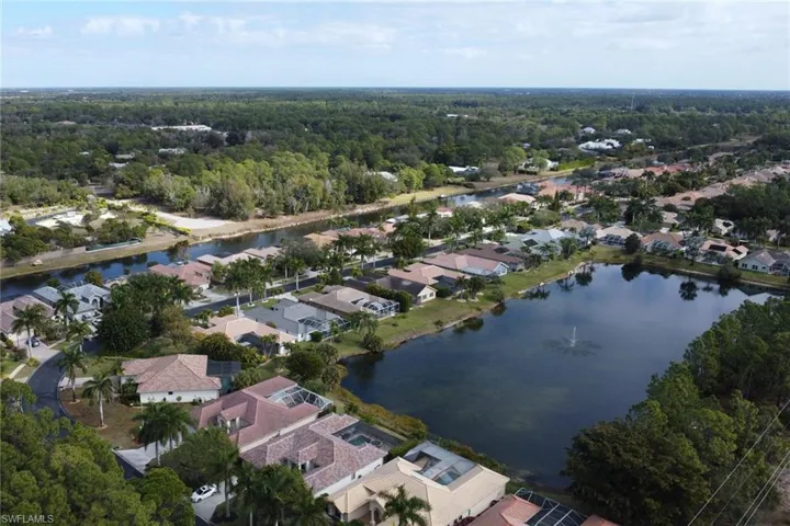 Aerial view of property and surrounding area featuring nearby suburban area and a large body of water