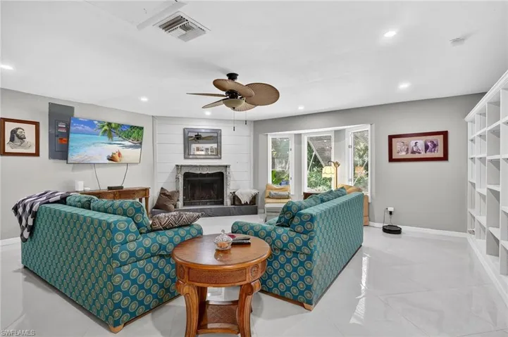 Living room with wall of built-in shelves and bay window. Raised fireplace and mounted TV that stays.