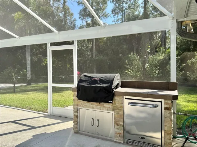 New outdoor kitchen with grill, refrigerator and storage.