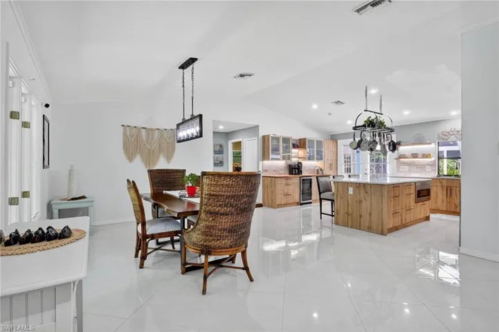 Open and bright dining and kitchen area with vaulted ceilings and center kitchen island.