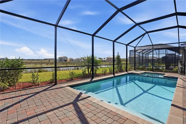 Integrated pool / hot tub with a sunroom, a lanai, a water view, a patio, and a residential view