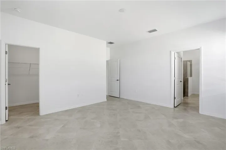 Unfurnished bedroom with a spacious closet and baseboards