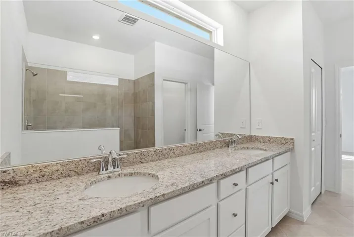 Full bathroom with double vanity, walk in shower, and light tile patterned floors