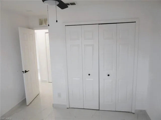 Unfurnished bedroom featuring a ceiling fan, a closet, and light marble finish floors