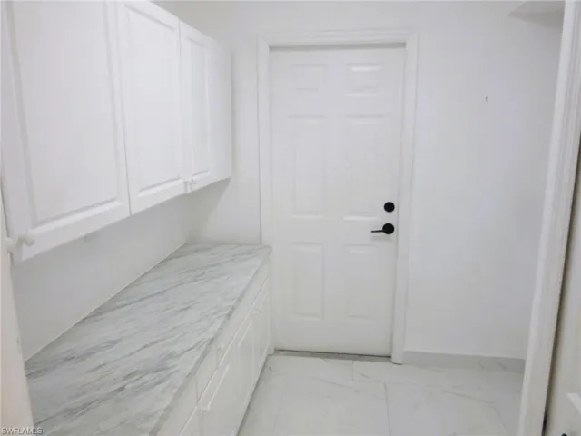 Laundry area with light marble finish floors and baseboards
