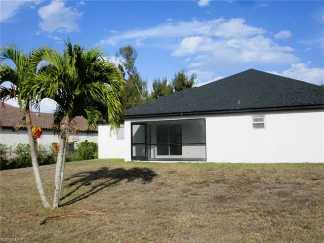 Rear view of property featuring a sunroom, a yard, stucco siding, and roof with shingles