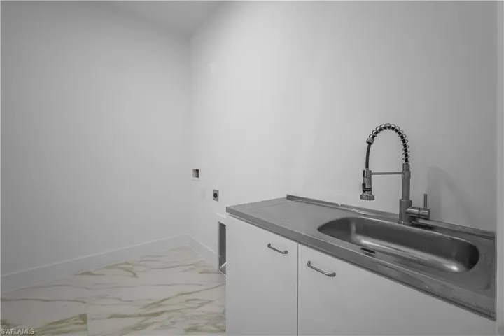Laundry room with light marble finish flooring, cabinet space, and hookup for an electric dryer