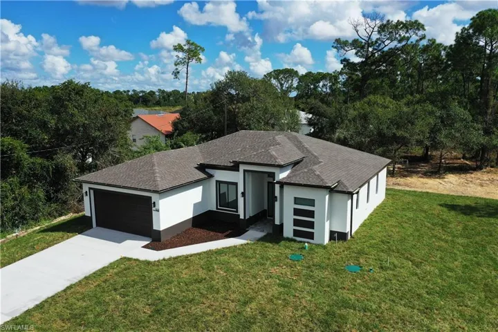 View of front of house with a front lawn, stucco siding, and a shingled roof