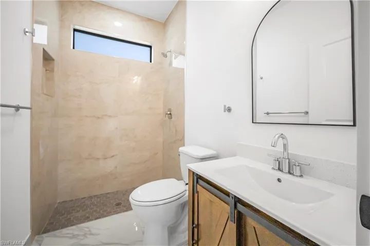 Bathroom featuring vanity, a marble finish shower, and marble finish flooring