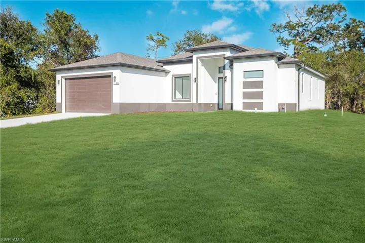 Prairie-style house with a front yard, a garage, stucco siding, concrete driveway, and roof with shingles