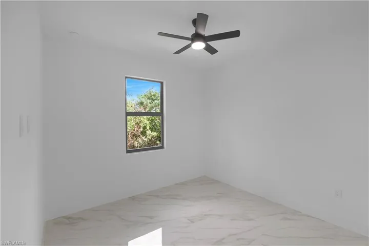 Spare room featuring light marble finish floors and a ceiling fan